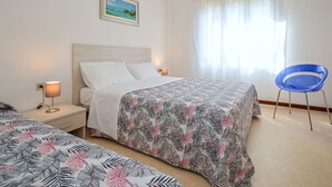 A hotel room with a bed, a chair, and a painting on the wall. - Villa Rosanna by Interhome (Lignano Pineta)