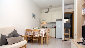 Ein gemütlicher Wohnbereich mit Sofa, Esstisch, Stühlen, einer Küchenzeile und einem Fernseher.