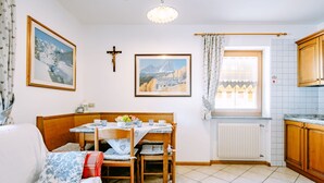 Kodikas huone, jossa on ruokapöytä, tuoleja, sohva ja ikkuna, jossa on verhot.