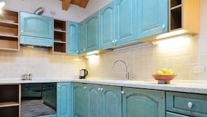 A kitchen with teal cabinets, a stainless steel sink, and a bowl of lemons on the counter. - Ardoney by Interhome (Campitello)
