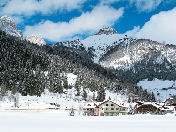 A snow-covered mountain with a chalet-style building in the foreground.