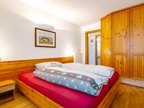 A bedroom with a wooden bed, a nightstand, a wardrobe, and a framed picture on the wall.