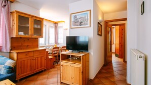 A compact kitchen with wooden cabinets, a dining area, and a television. - Cesa Pra da Molin by Interhome (Campitello)