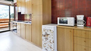 Eine moderne Küche mit Holzschränken, einem Geschirrspüler, einer Mikrowelle und einer Kaffeemaschine.