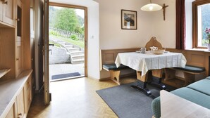Een gezellige kamer met een houten plafond, een bankje, een tafel met een wit tafelkleed en een raam met uitzicht op een tuin.