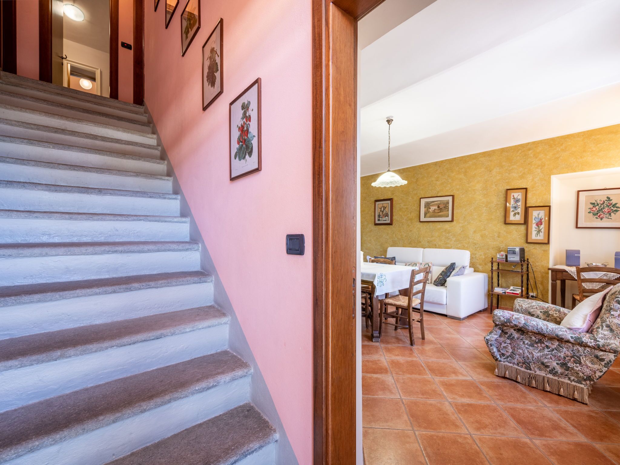 A staircase leading to a living area with a sofa, a dining table, and a chair.