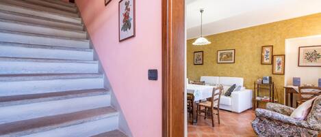 A staircase leading to a living area with a sofa, a dining table, and a chair.