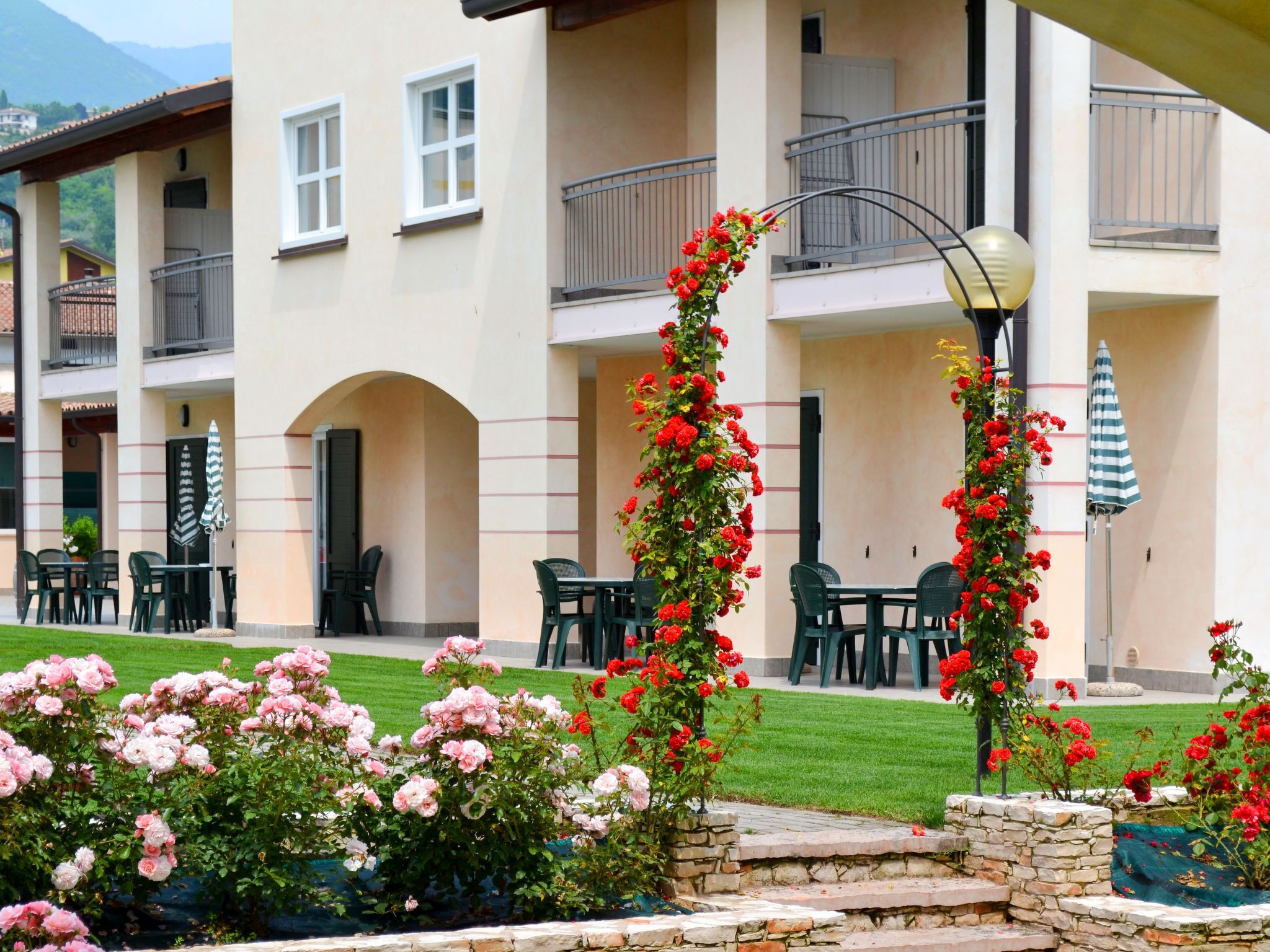 A hotel courtyard with outdoor seating, a stone staircase, and a flower garden.