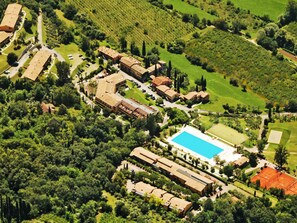 An aerial view of a resort with multiple buildings, a swimming pool, and surrounding greenery.