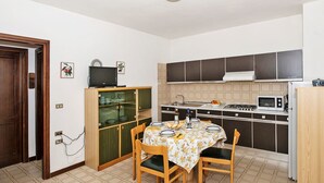 Une cuisine compacte comprenant une table à manger, des chaises, un four à micro-ondes et une cuisinière.
