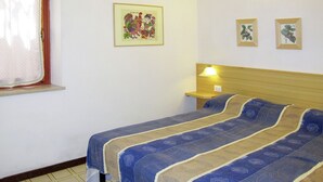 Une chambre à coucher avec un lit, une table de chevet, une lampe et une fenêtre avec des rideaux.
