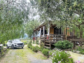 Une cabane dotée d’une terrasse en bois, d’un porche couvert et d’une allée gravillonnée.