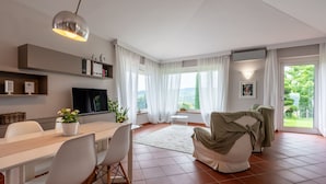 A modern living room with a dining area, a television, and a view of the outdoors.
