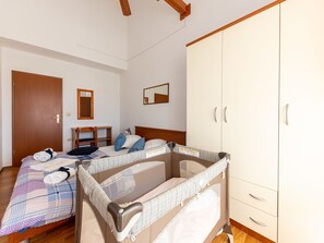Quarto de hotel com cama, escrivaninha, guarda-roupa e espelho.