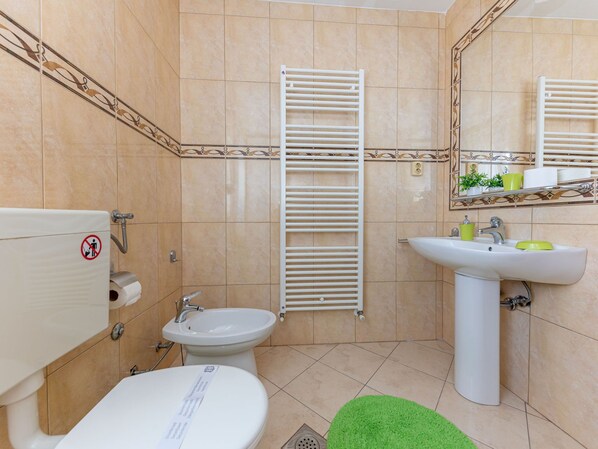 Un baño con inodoro, bidé, lavamanos y barras para toallas.
