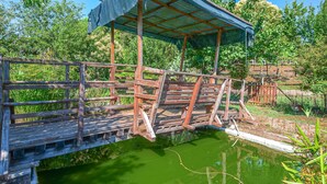 Eine Holzbrücke über einem Teich mit einem überdachten Schutzhaus.
