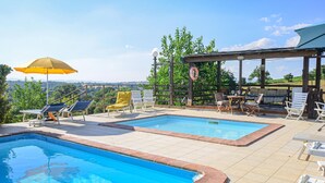 Ein Poolbereich mit zwei Pools, Liegestühlen und einer überdachten Sitzgelegenheit.