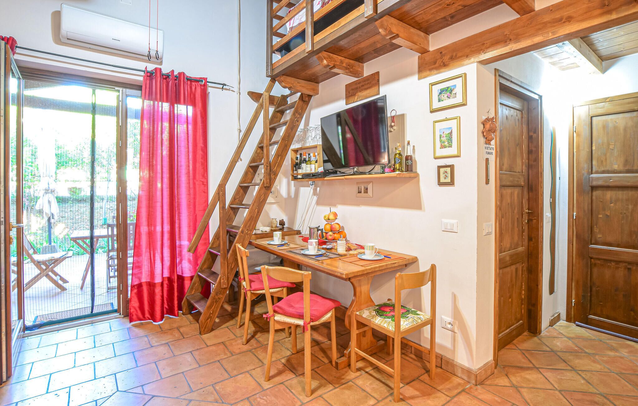 Una habitación acogedora con una mesa de madera, sillas, un televisor y una escalera.