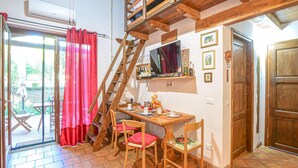 Ein gemütliches Zimmer mit einem Holztisch, Stühlen, einem Fernseher und einer Leiter.