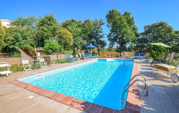 Une piscine rectangulaire à l’eau d’un bleu limpide, entourée d’une terrasse carrelée.