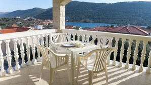 A balcony with a table and chairs, overlooking a mountainous landscape and a body of water. - Apartment Toni by Interhome (Šibenik)
