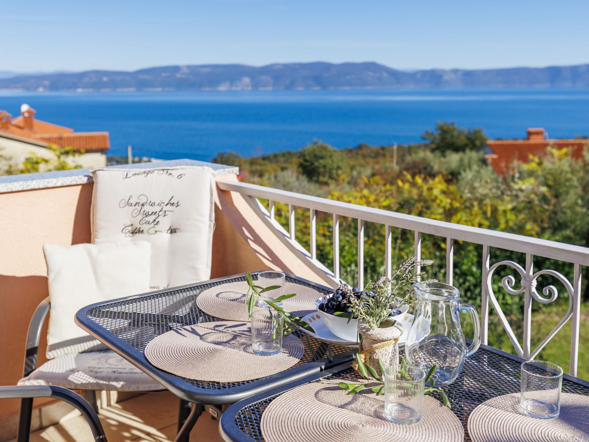 Eine Terrasse mit gedecktem Tisch für zwei Personen, mit Blick auf eine malerische Küstenlandschaft.