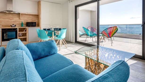 A modern living room with a sofa, a glass coffee table, and a view of the ocean through large sliding doors. - La Palangre by Interhome (Argelès sur Mer)