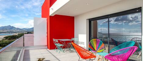 A modern balcony with colorful chairs and a glass railing overlooking a scenic landscape.