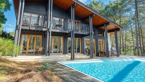 Una casa moderna de dos pisos con terraza de madera y piscina.