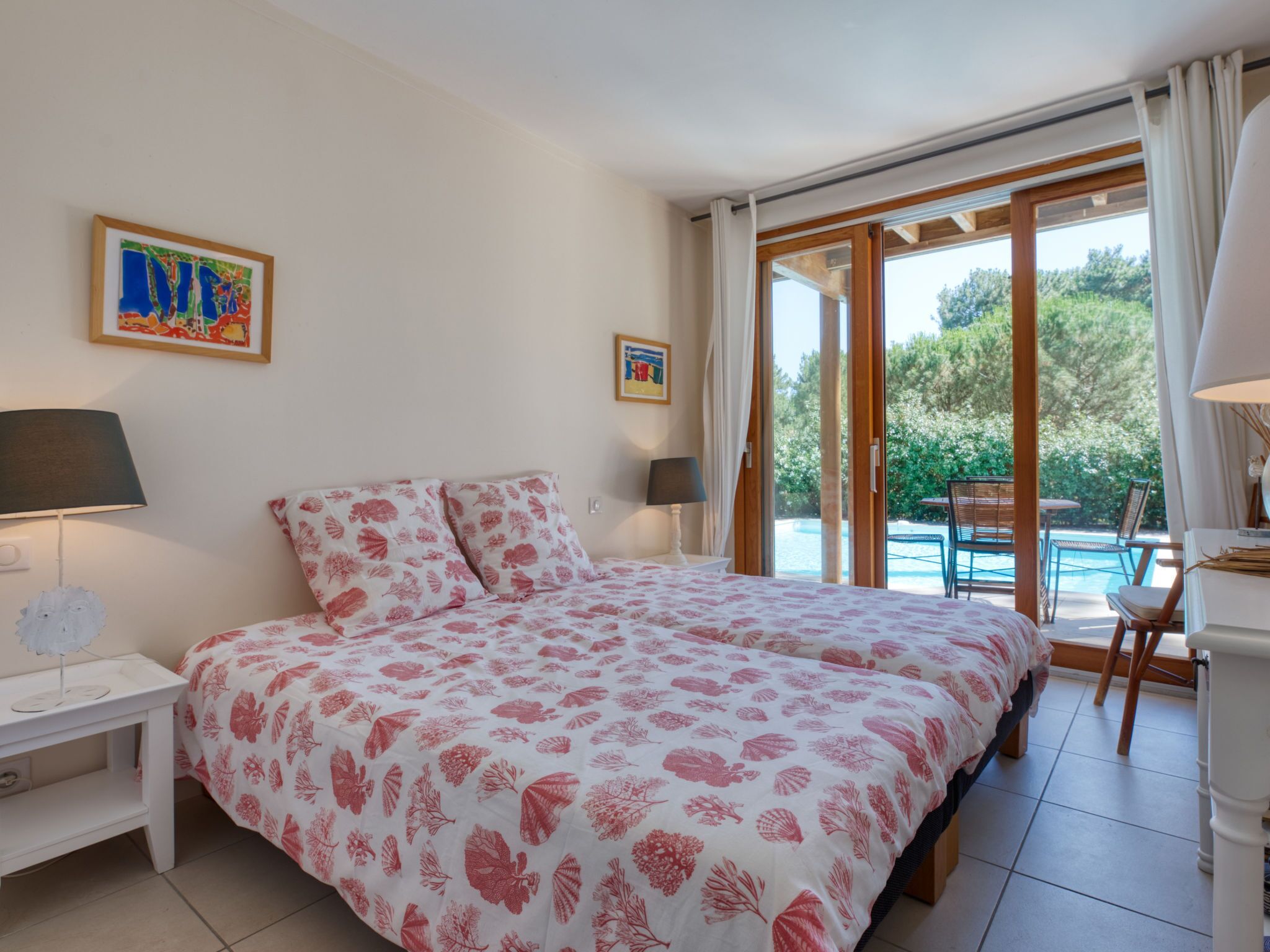 Une chambre avec un grand lit, deux tables de chevet et une vue sur une piscine.