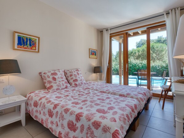 Un dormitorio con una cama grande, dos mesitas de noche y vistas a una piscina.