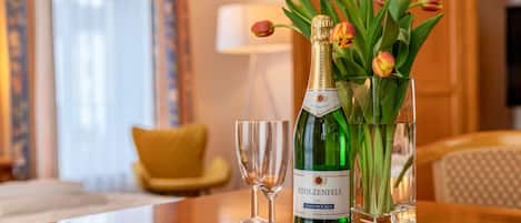 A bottle of Stolzenfels wine, a glass, and a vase with tulips on a wooden table.