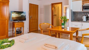 A hotel room with a bed, a TV, a wooden cabinet, a table with a bottle of champagne, and a kitchenette. - Stolzenfels by Interhome (Ostseebad Sellin)