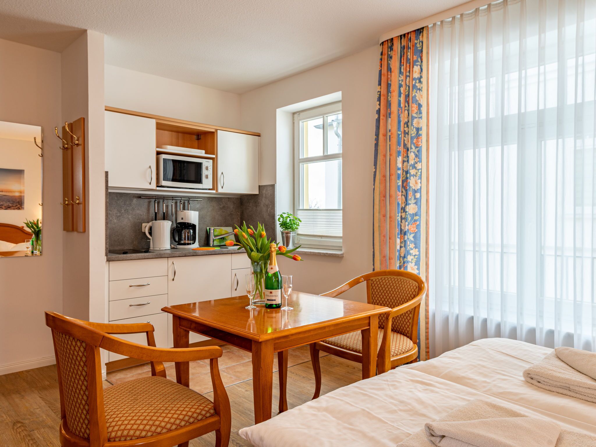 Ein kleines Hotelzimmer mit Küchenzeile, Essbereich und einem Bett.