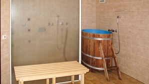 A bathroom with a wooden barrel sink, a bench, and a shower area.