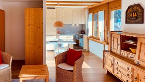 Una habitación acogedora con muebles de mimbre, una mesa de comedor de madera y una cocina visible a través de una puerta abierta.