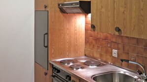 Eine Küche mit Holzschränken, einer Edelstahlspüle und einem Einbauofen.