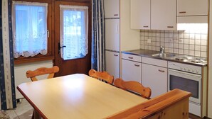Eine kleine Küche mit Holztisch und Stühlen, einem Herd und Schränken.