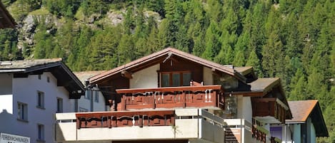 Hotel met balkon, Coca-Cola reclamebord en een berg op de achtergrond.