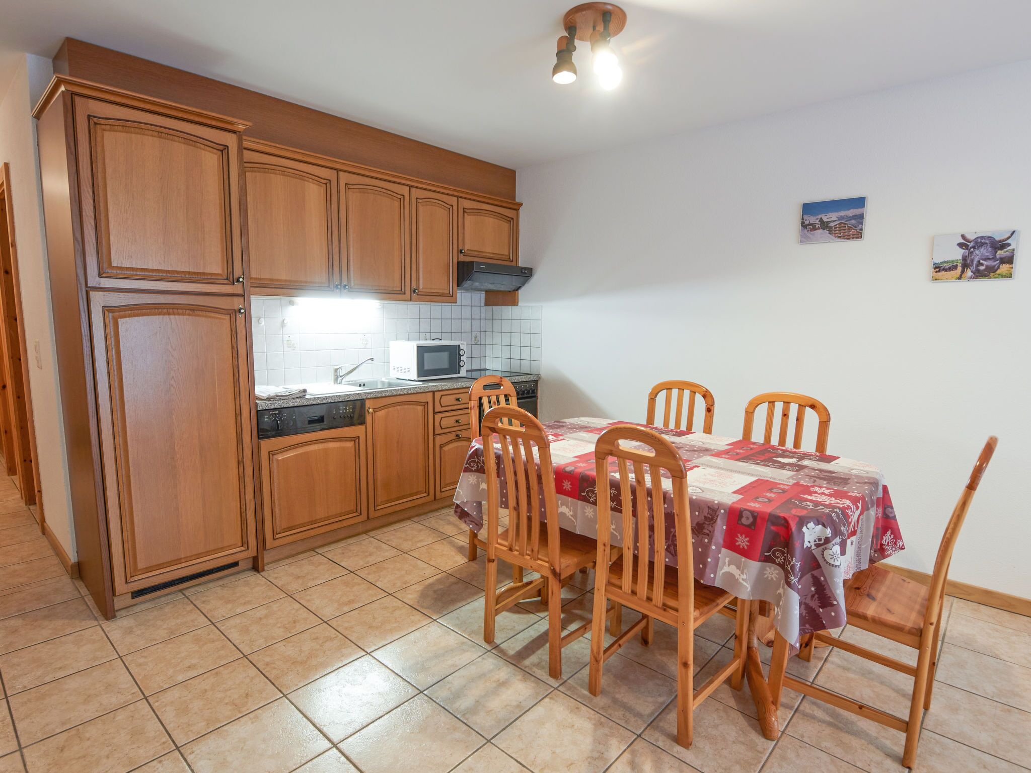 A kitchen with wooden cabinets, a microwave, and a dining table with chairs.