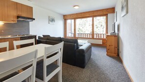 Et lille køkken med spiseplads, sofa og tv.