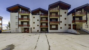 A multi-story hotel with balconies, a central courtyard, and a parking area. - Hameau D01 by Interhome (Thyon-Les Collons)