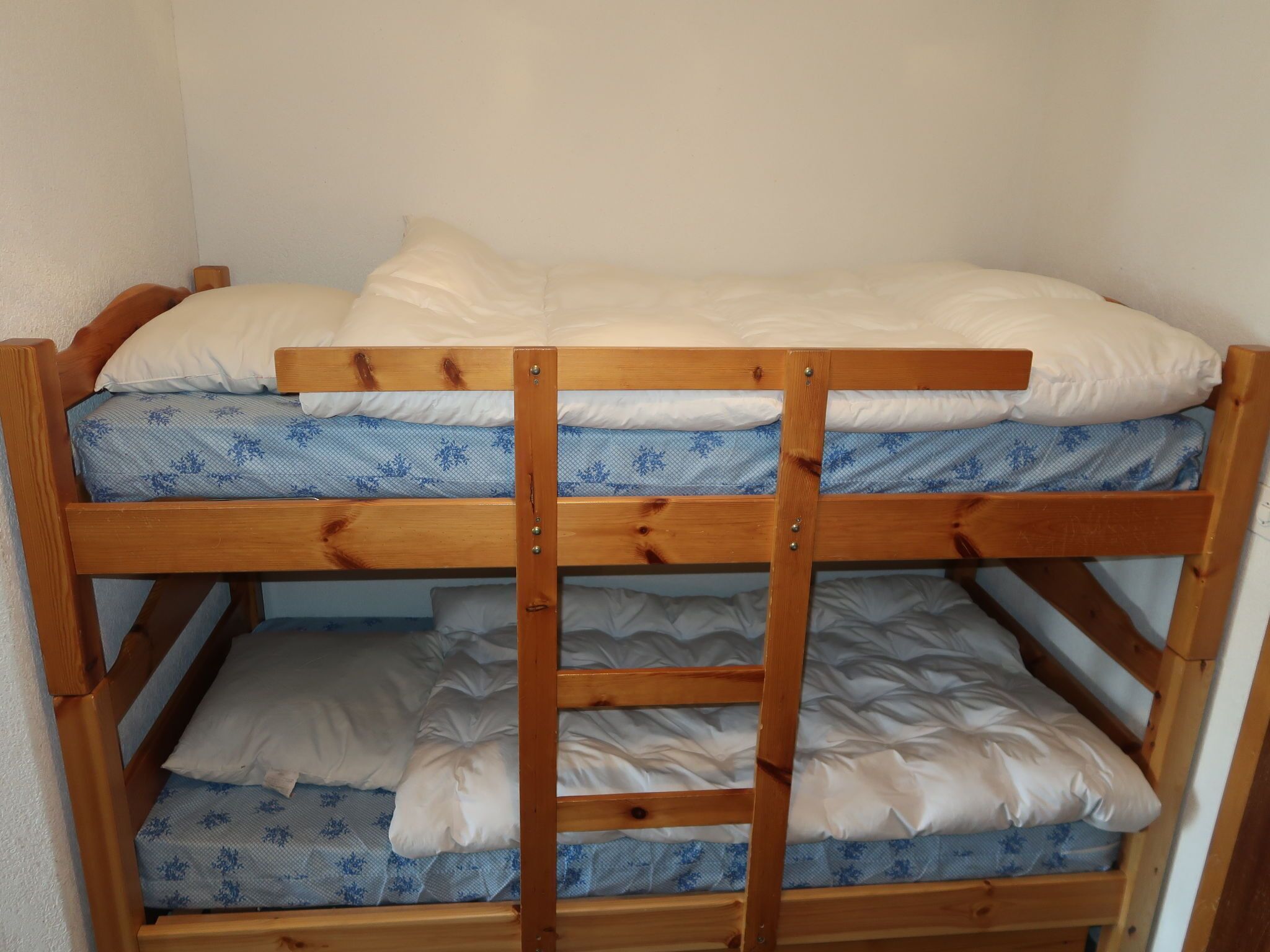 Ein Etagenbett mit zwei Schlafstellen, jeweils mit einer Matratze und Kissen.