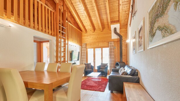 A wooden interior with a dining area, a sofa, and a fireplace.
