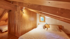 A wooden room with a bed, a window, and a door.