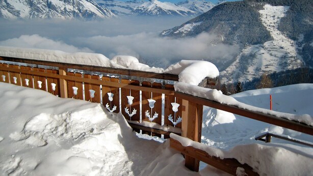 A wooden fence with snow accumulation, overlooking a mountainous landscape with snow-covered peaks and a valley below. - Edelweiss by Interhome (La Tzoumaz)