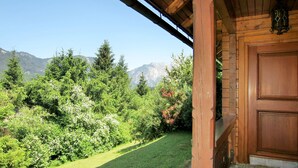 A wooden cabin with a door and a view of a lush garden and mountains. - Simons Blockhütte by Interhome (Gröbming)