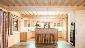 Una cocina moderna con armarios de madera, una isla central con taburetes y un horno empotrado.