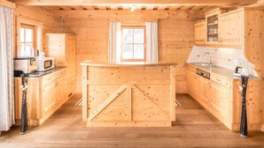 Interior de una cabaña de madera con una cocina, muebles de madera y un ventanal.