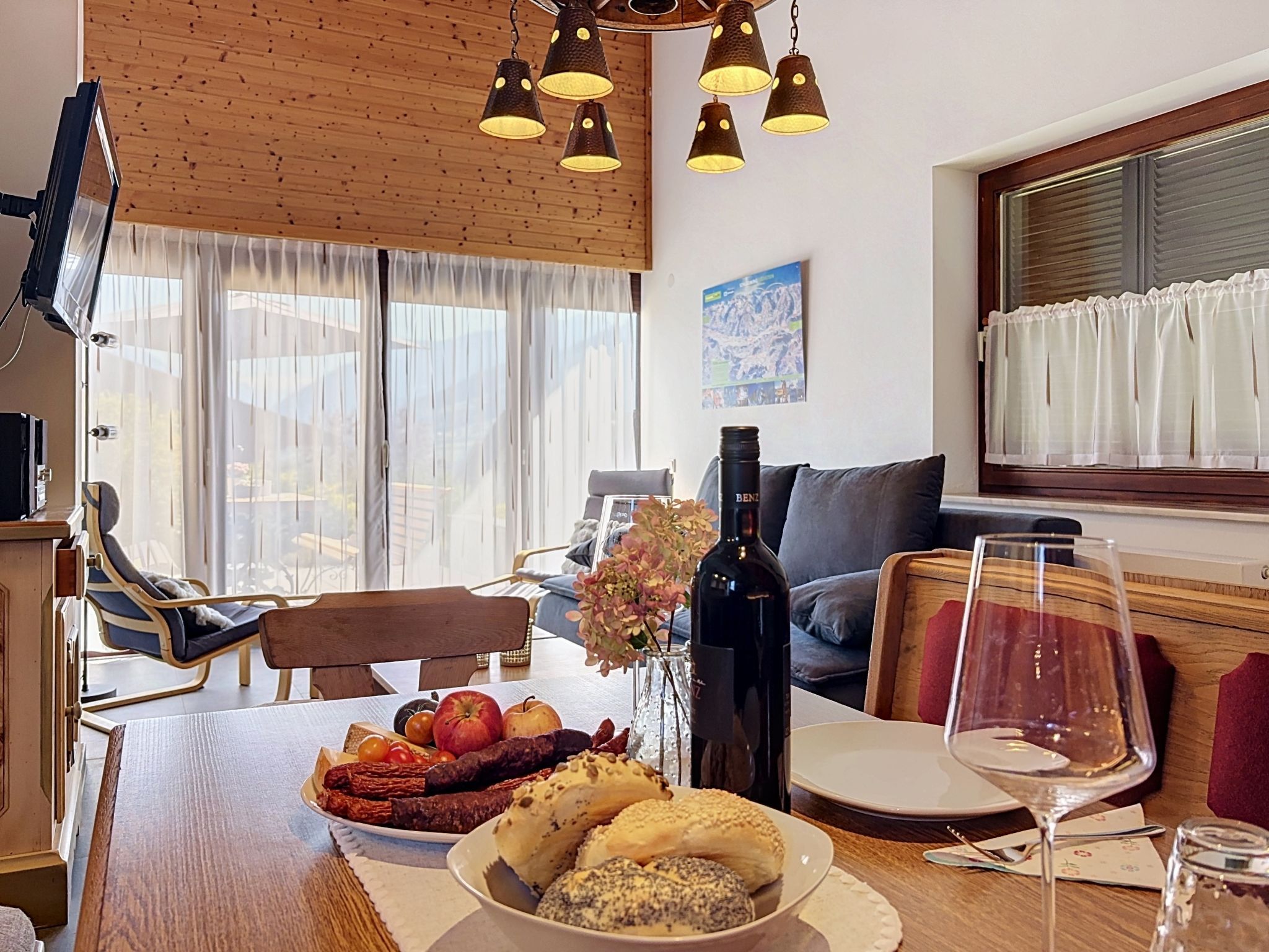 A dining area with a wooden table set for a meal, a bottle of wine, and a glass on the table.